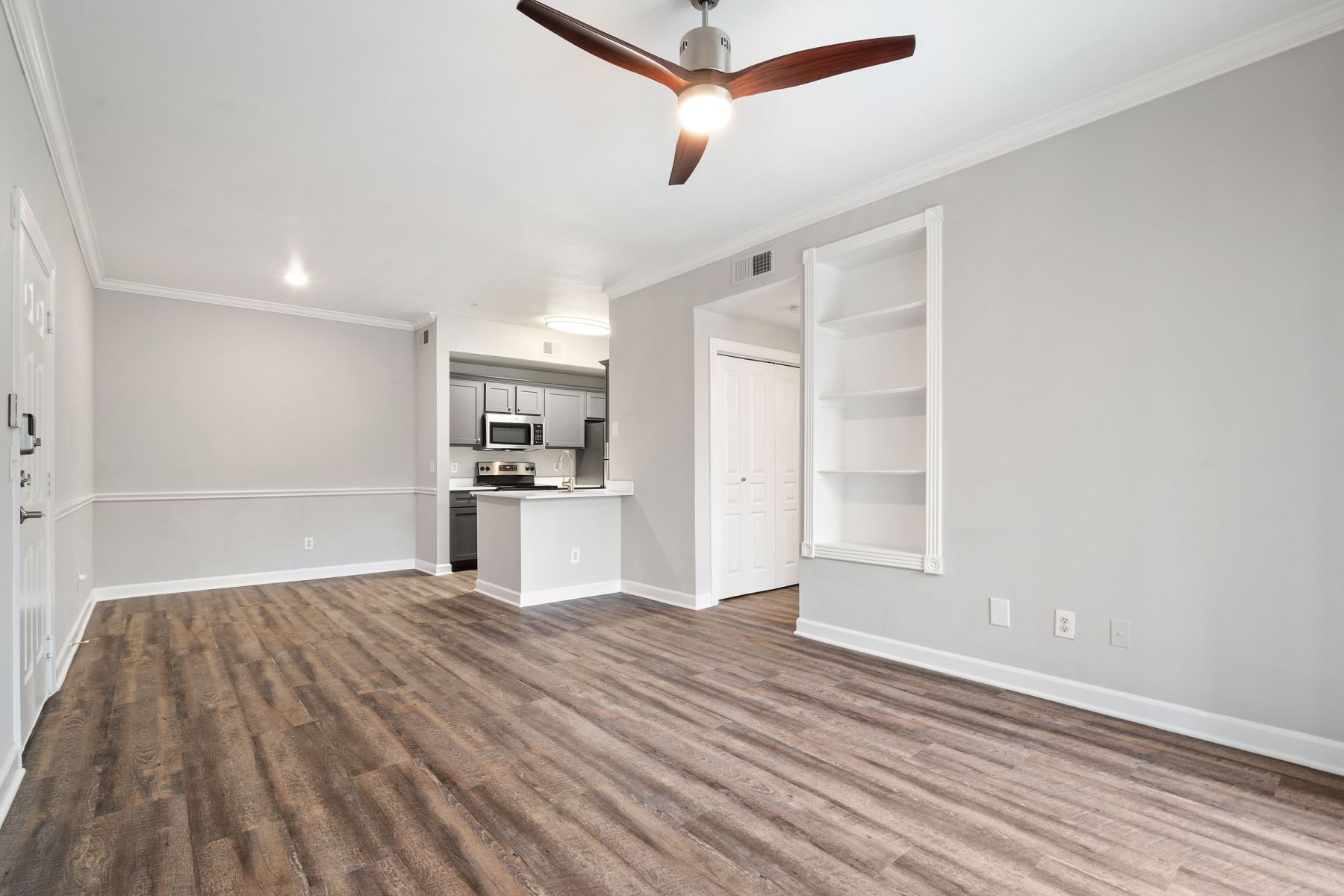 Empty room with wood floors, ceiling fan, and sliding glass door leading to a patio with vertical blinds at Apex West Midown.